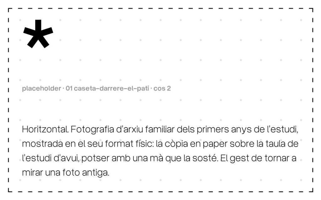 Horitzontal. Fotografia d'arxiu familiar dels primers anys de l'estudi, mostrada en el seu format físic: la còpia en paper sobre la taula de l'estudi d'avui, potser amb una mà que la sosté. El gest de tornar a mirar una foto antiga.