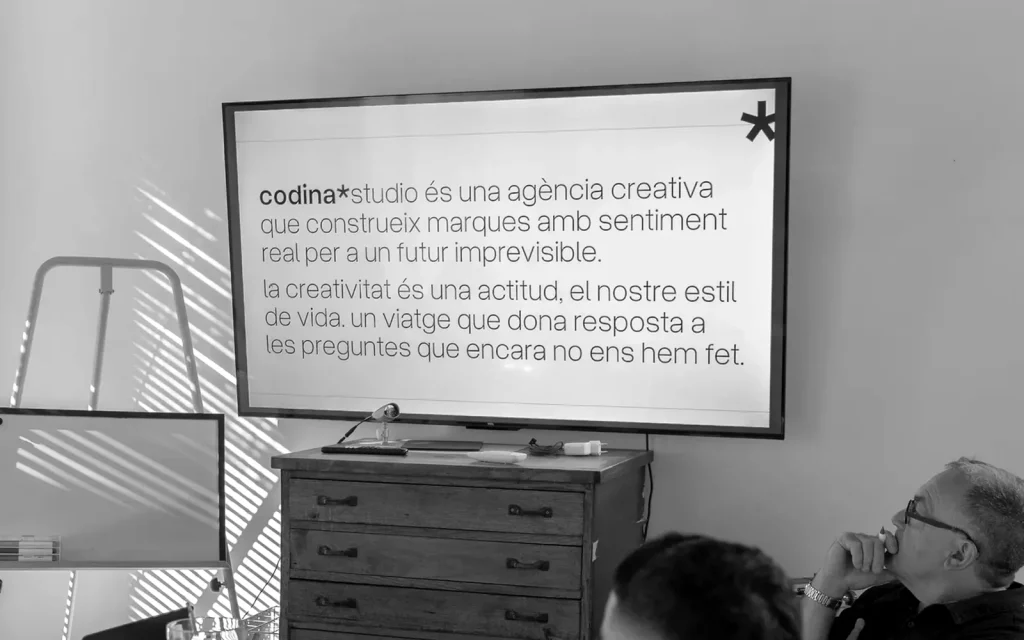 Dues persones mirant una proposta projectada a la pantalla de la sala de l'estudi.