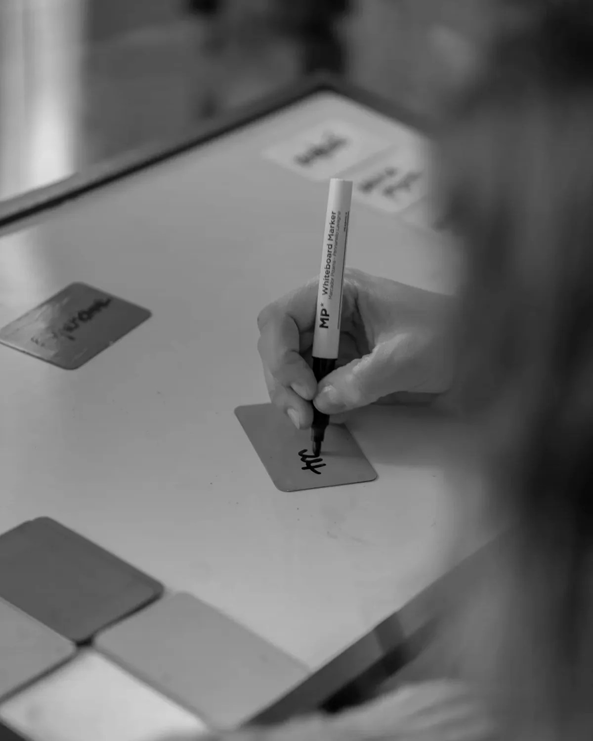 Una mà escrivint sobre una targeta de treball, en primer pla.