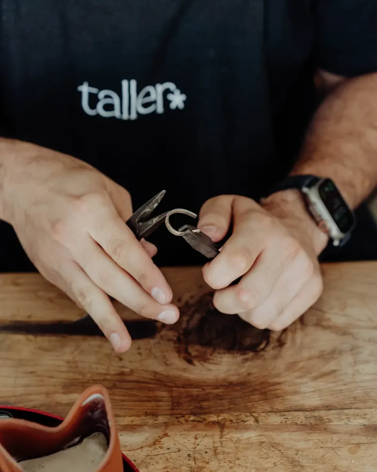 Unes mans treballant una peça de metall al banc del taller de joieria.